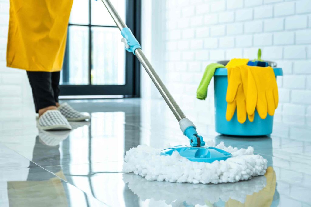 Ein Mitarbeiter eines professionellen Reinigungsinstituts wäscht sorgfältig den Boden, um Sauberkeit und Hygiene in einem Gebäude zu gewährleisten.